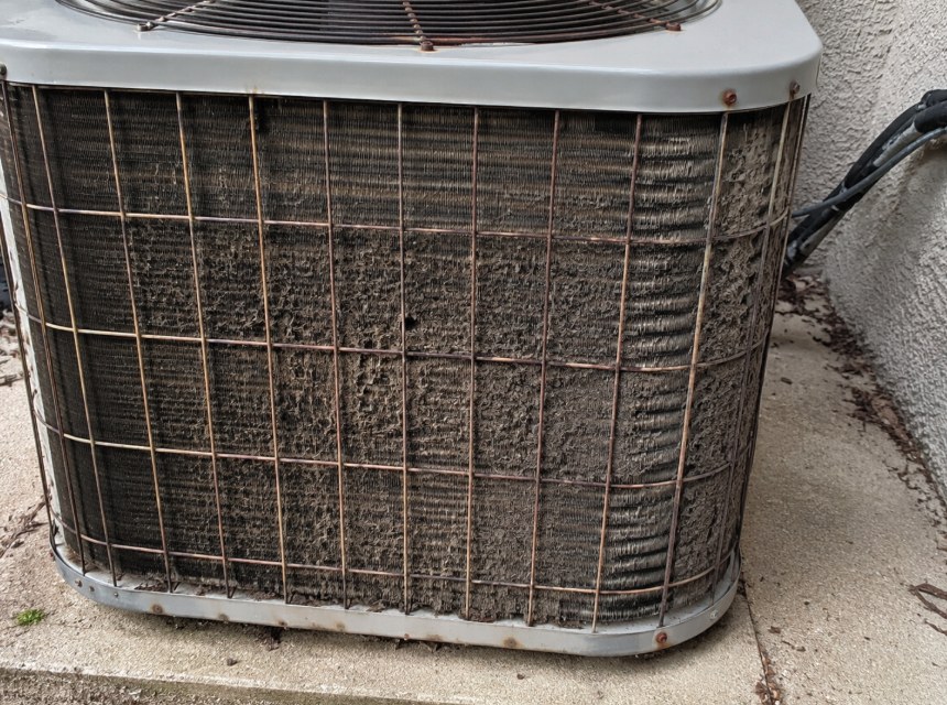 Dirty outdoor air conditioner condenser coil restricting airflow and reducing cooling efficiency.